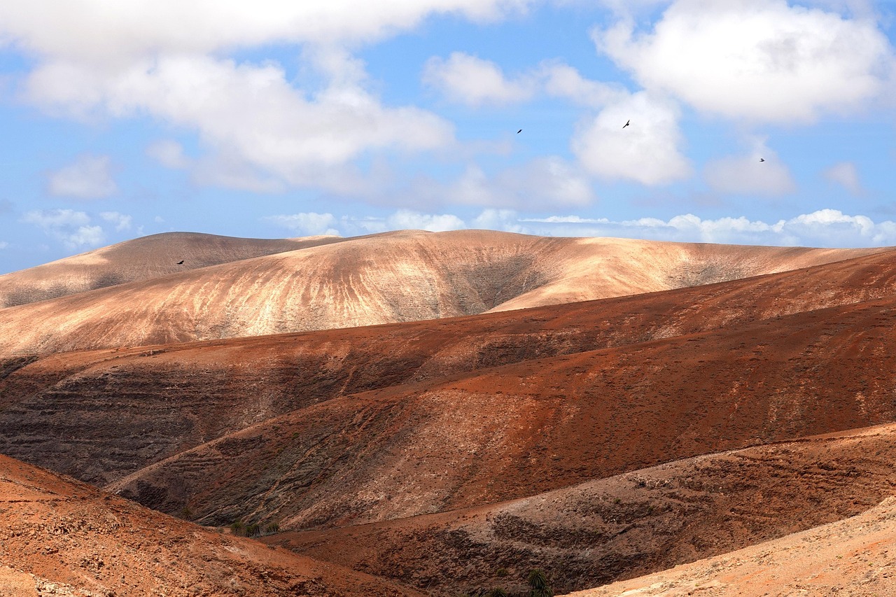 Empty sand dunes and hills beneath a cloudy sky